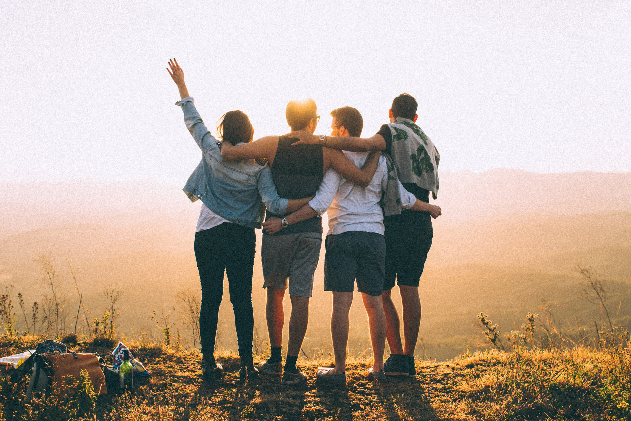 Anonymous friends standing together at sunset in mountains